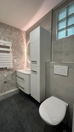 une salle de bain blanche avec des toilettes et un lavabo dans l'établissement Le Notre-Dame - Au coeur des Chartrons, à Bordeaux