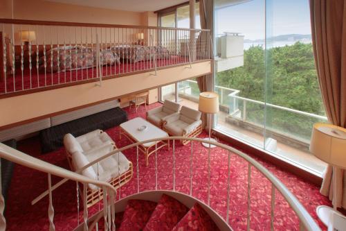 a room with a balcony with chairs and a table at Kamogawa Grand Hotel in Kamogawa