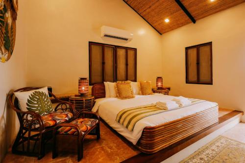 a bedroom with a large bed and two chairs at Nawa Wellness in Calatagan