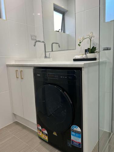 a black dishwasher under a sink in a bathroom at Redvue Holiday Apartments in Redcliffe