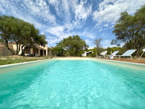 une grande piscine avec des chaises et une maison dans l'établissement Mas Provençal Privé avec Piscine sans vis à vis en plein Cœur du Luberon, à La Motte-dʼAigues