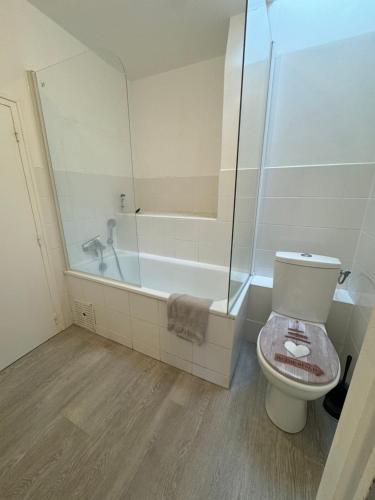 La salle de bains est pourvue d'une douche, de toilettes et d'une baignoire. dans l'établissement Le CulSalé joli studio au cœur des remparts avec vue imprenable sur les toits, à Guérande