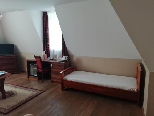 a small room with a bed and a desk and a chair at Batthyány Kastélyszálló in Zalacsány