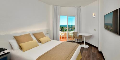 1 dormitorio con 1 cama y balcón con mesa en Sol Palmanova All Inclusive, en Palmanova