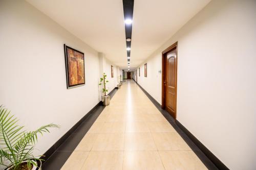 a corridor with white walls and a long hallway with plants at Hotel One Sargodha in Sargodha