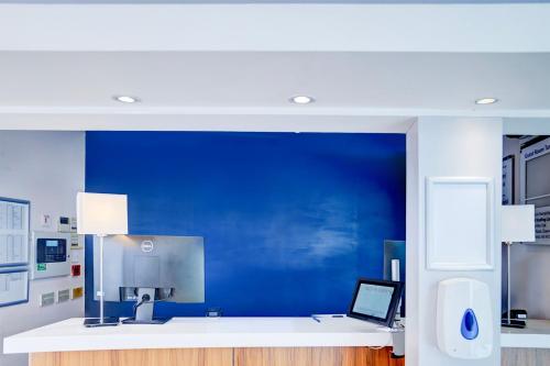 an office with a blue wall and a desk with a laptop at Belvilla Crewe City Centre Lifestyle in Crewe