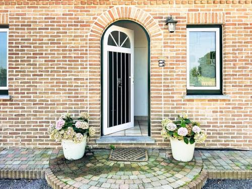 a brick house with two potted plants in front of a door at Modern Loft with 2 bedrooms near Sint Truiden in Herk-de-Stad