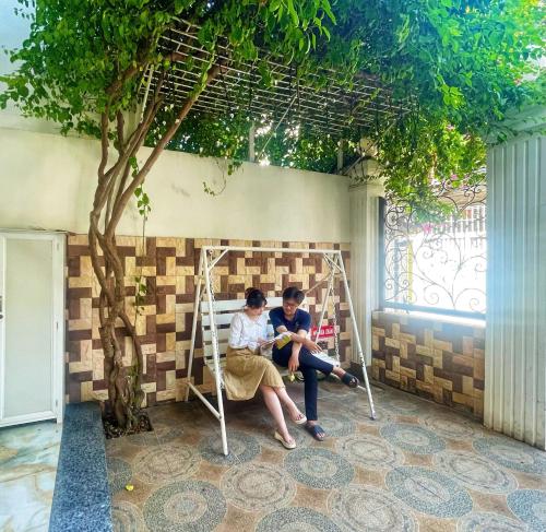 two children sitting on a swing under a tree at Joi Home The Hidden Villa in Vung Tau