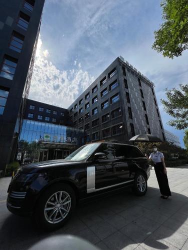 a man standing next to a black limo in front of a building at Jingli Hotel - Beijing New National Exhibition Capital Airport in Houshayu