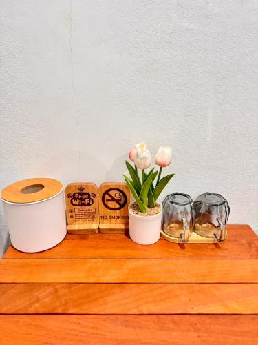 a wooden shelf with flowers and other items on it at สบายดีห้องเช่า รายวัน รายเดือน in Sa Kaeo