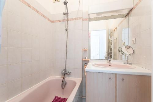une salle de bain avec un lavabo, une baignoire et un miroir dans l'établissement Le Domaine du Golf - Appt vue mer avec piscine, à Sète