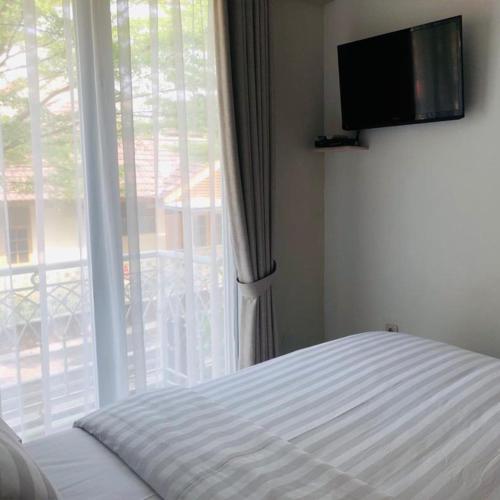 a bedroom with a bed and a large window at Bening Boutique Hotel Managed By Salak Hospitality in Cibening Tiga