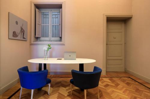a table with two blue chairs and a laptop on it at Belmonte LR Collection in Palermo