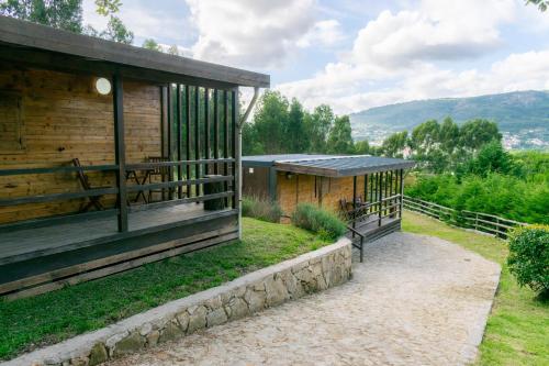 a wooden building with a porch next to a path at Naturena Agro-Turismo in Durrães