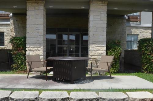 a table with chairs and a trash can in front of a building at Country Inn & Suites by Radisson, Austin North Pflugerville , TX in Round Rock