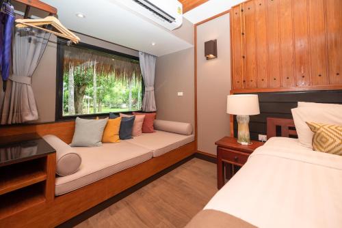 a living room with two beds and a window at River Kwai Resotel in Sai Yok