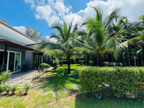 a yard with palm trees next to a house at Marisa Garden Bungalow in Bang Tao Beach