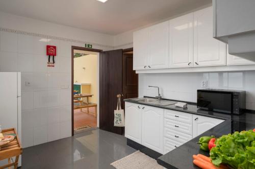 a kitchen with white cabinets and a counter top at Casa Amarela da Fajã da Areia by An Island Apart in São Vicente