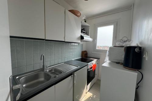 une cuisine avec des armoires blanches, un évier et une fenêtre dans l'établissement Nice T2 close to the beach of Cabourg, à Cabourg