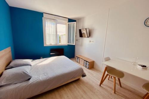 - une chambre avec un mur bleu, un lit et un bureau dans l'établissement Cosy apartment 5 min to the center of La Rochelle, à La Rochelle