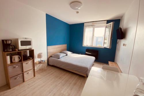 une chambre avec un lit et un mur bleu dans l'établissement Cosy apartment 5 min to the center of La Rochelle, à La Rochelle