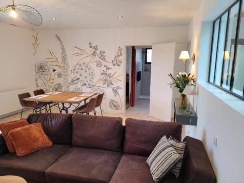 a living room with a brown couch and a table at 2 Gites dans les remparts à Dun sur Meuse in Dun-sur-Meuse