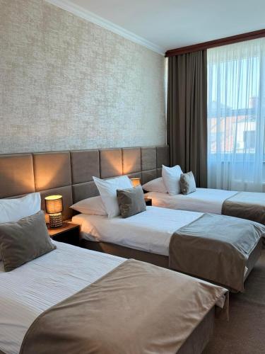 a hotel room with three beds and a window at Hotel Vidović in Banja Luka