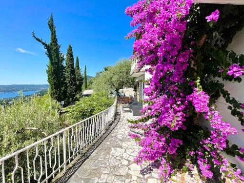 a walkway with purple flowers on a building at Villa Licia in Gardone Riviera