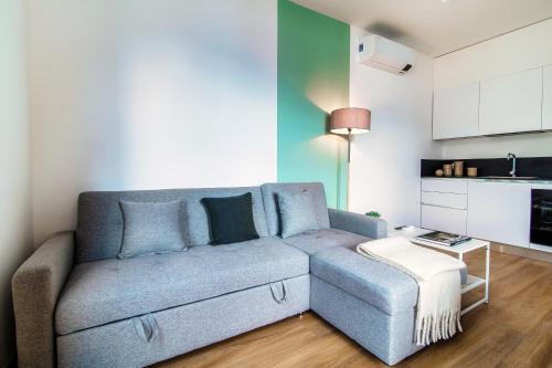 a living room with a blue couch and a kitchen at Agastache & Salvia - by MyHomeInComo in Menaggio