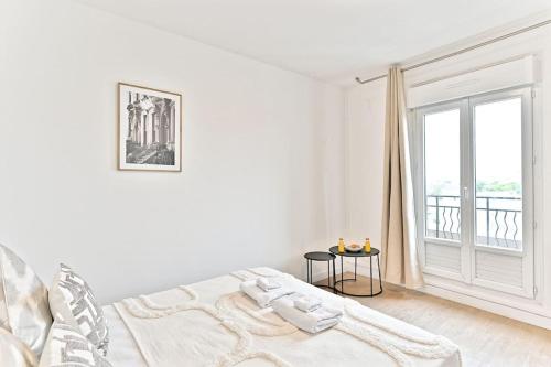 ein weißes Schlafzimmer mit einem Bett und einem Fenster in der Unterkunft Studio lumineux et moderne à Montreuil - II in Montreuil