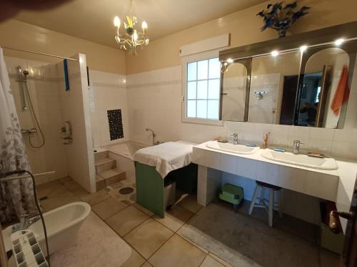 une salle de bain avec deux lavabos et une baignoire et une baignoire dans l'établissement Maison de famille 8-9 personnes, à Saint-Hilaire-Peyroux