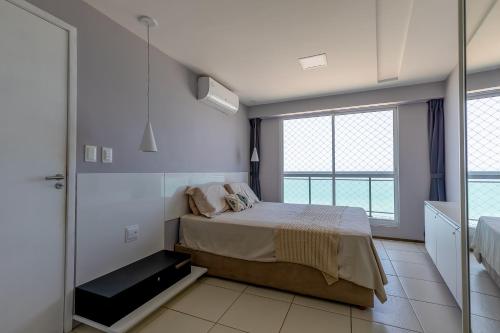 a bedroom with a bed and a large window at Modern Beachfront Apartment w. Magnificent Seaview in Fortaleza