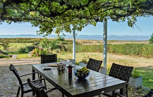 einen Holztisch mit Stühlen und eine Schale mit Obst darauf in der Unterkunft Nice Home In Bogø By With Wifi in Bogø By