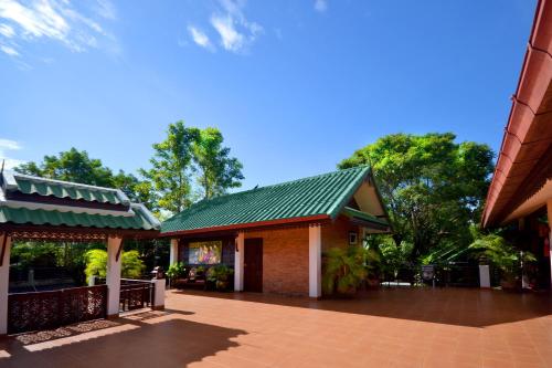 a house with a green roof and a patio at Thai Thai Sukhothai Resort in Sukhothai