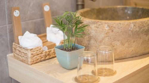 a bathroom counter with a sink and a plant and two glasses at Dashe Yuanye Boutique Homestay in Xitang