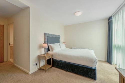 a bedroom with a bed and a lamp on a table at Princes Street Suites in Edinburgh