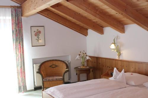 a bedroom with a bed and a chair at Kurhotel Rupertus in Bad Reichenhall