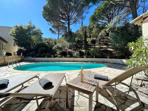- une piscine avec 2 chaises et une table avec une bouteille de vin dans l'établissement Seaview Villa Petit Prince, Pool, air conditioning, à Sainte-Maxime
