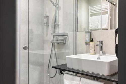 a white bathroom with a sink and a shower at Nena Apartments München City in Munich