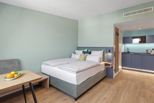 a bedroom with a bed and a table and a kitchen at Nena Apartments München City in Munich