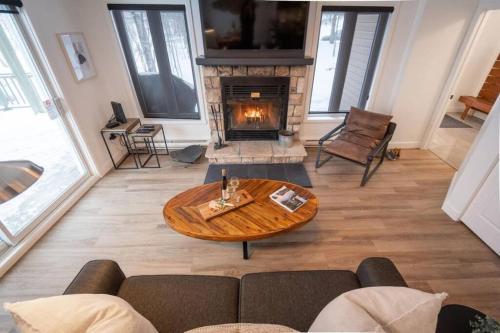 a living room with a table and a fireplace at L'Érablière Tremblant Ski Inout Condo W 2bdrs in Mont-Tremblant