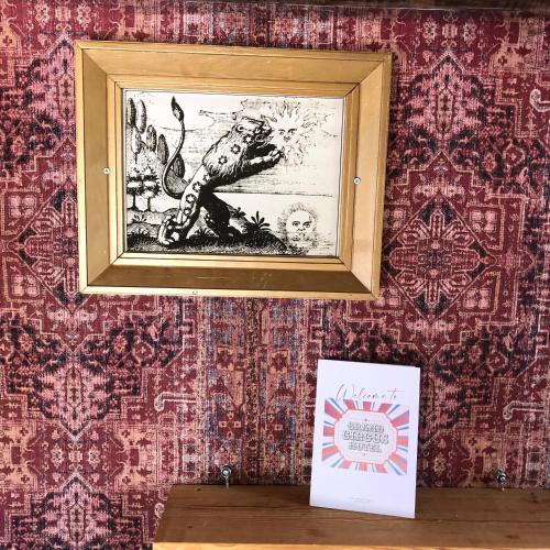 a framed picture on a wall with red wallpaper at Grand Circus Hotel in Malmö