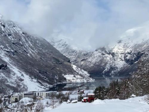 a snow covered mountain with a river and a train at Tømmerhus i Geiranger Sentrum med panorama utsikt in Geiranger