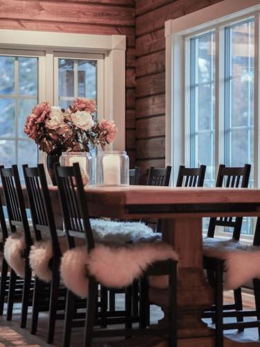 a wooden table with chairs and a vase of flowers at Tømmerhus i Geiranger Sentrum med panorama utsikt in Geiranger
