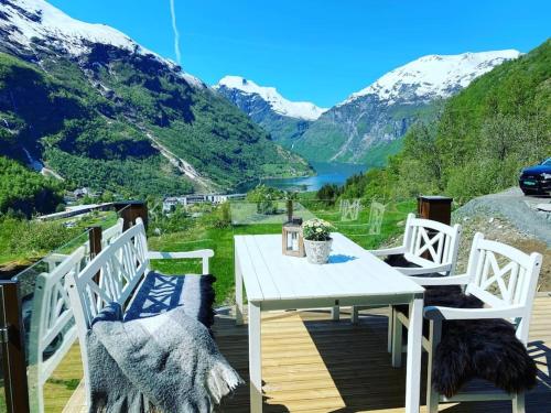 a table and chairs on a deck with a view of a mountain at Tømmerhus i Geiranger Sentrum med panorama utsikt in Geiranger