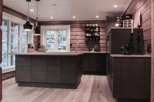 a kitchen with wooden walls and a large kitchen island at Tømmerhus i Geiranger Sentrum med panorama utsikt in Geiranger