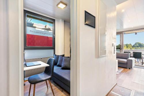 a living room with a couch and a desk with a laptop at Hausboot Joana in Zehdenick
