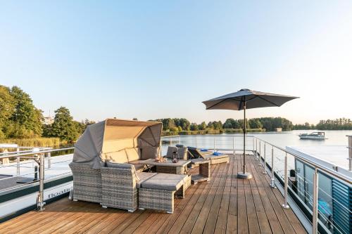 a deck with chairs and an umbrella on a body of water at Hausboot Joana in Zehdenick
