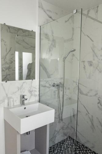 une salle de bain blanche avec un lavabo et une douche dans l'établissement New Hôtel Gare Du Nord, à Paris