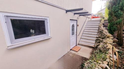 a white building with a window and a staircase at Ruheoase am Waldrand - auf 90qm sind nicht nur die Eltern und bis zu 5 Kinder willkommen, auch Hunde und Katzen sind willkommen in Laichingen